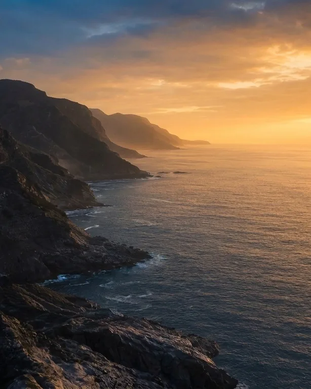 A coastline at golden hour, the sea lit gold to the horizon